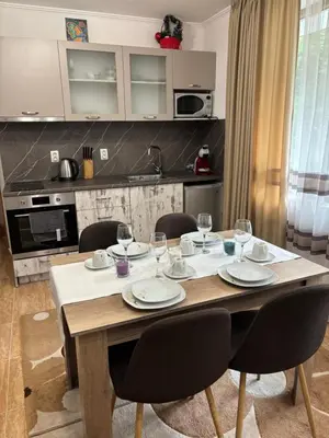 a dining room table with chairs and a kitchen at Апартамент за гости 4а26 Планинска Магия Grand Monastery Пампорово in Pamporovo