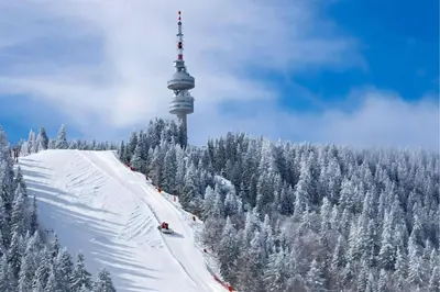 a snow covered hill with a ski slope with a tower at Studio Elegance Pamporovo in Pamporovo