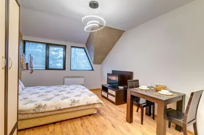 a bedroom with a bed and a desk and a table at Студио Ая- Смолянски езера in Smolyan