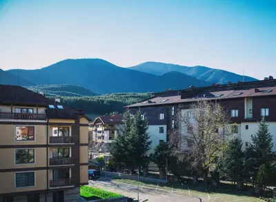 a group of buildings with mountains in the background at New White Studio F next to Forest the Gondola in Bansko