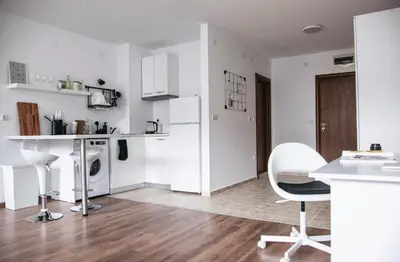 a kitchen with white cabinets and a table and chairs at New White Studio F next to Forest the Gondola in Bansko