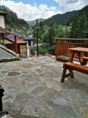 a wooden bench sitting on top of a stone patio at Майоровата къща in Shiroka Lŭka