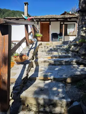 a stone walkway leading to a house with a porch at Майоровата къща in Shiroka Lŭka