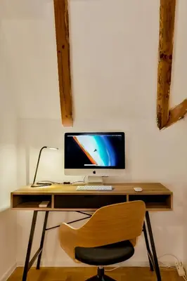 a wooden desk with a computer monitor and a chair at Dreamy Sunset Loft in Sofia City Center in Sofia