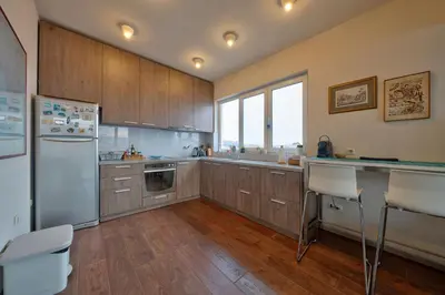 a kitchen with wooden cabinets and a white refrigerator at Sofia center best view by Flat Mаnager in Sofia
