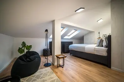 a bedroom with a bed and a chair in a room at ARHEYA 8 apart/АРХЕЯ 8 апартамент за гости in Karlovo