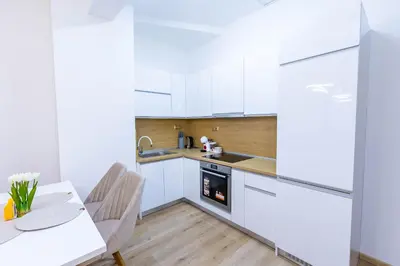 a kitchen with white cabinets and a table and a sink at Bellalux in Sandanski