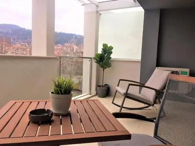 a room with a table and a chair and a balcony at Sky Apartments in Blagoevgrad