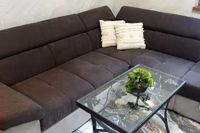 a brown couch with a glass table in a living room at АПАРТАМЕНТ WISH in Pamporovo