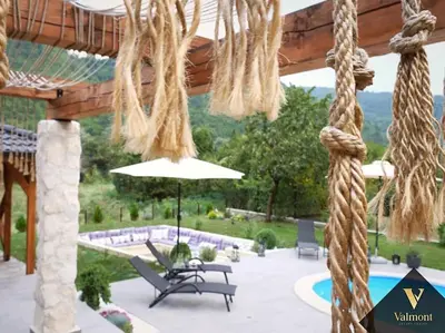 a patio with a umbrella and chairs and a pool at Valmont Luxury Chalet in Glozhene