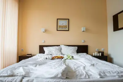 a white bed with a bowl of flowers on it at Хотел Дикас in Smolyan
