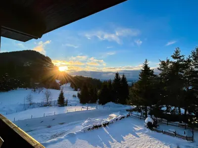 a winter view of a snow covered slope with the sun setting at OAK PARADISE in Smolyan
