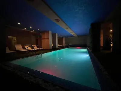 a large swimming pool in a hotel at night at Charming comfortable apartment at Cornelia Deluxe Residence with free pool and SPA in Razlog