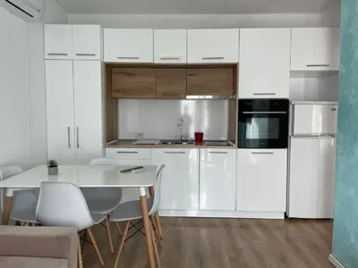 a kitchen with white cabinets and a table and chairs at Charming comfortable apartment at Cornelia Deluxe Residence with free pool and SPA in Razlog
