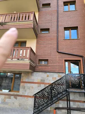 a finger pointing at a building with a balcony at Beautiful Apartment in Bansko