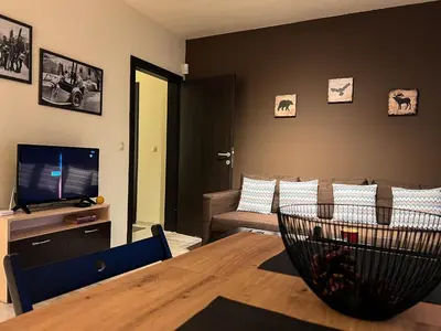 a living room with a table and a television at Elite Apartments Complex Iglika Borovets in Borovets