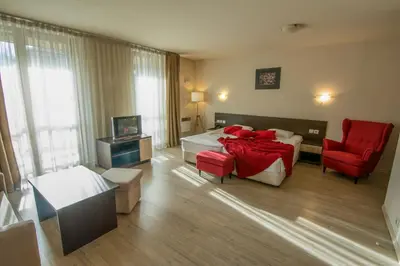a hotel room with two beds and a red chair at Banderitsa Apartment 2 in Bansko