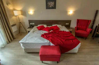 a bedroom with a bed and two red chairs at Banderitsa Apartment 3 in Bansko