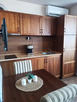 a kitchen with a table and a sink and wooden cabinets at Sunrise View with Free SPA and Bottle of Wine in Cornelia Deluxe Residence, free Parking in Bansko