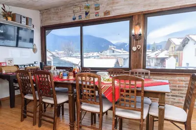 a dining room with a table and chairs and a large window at Chalet Garibaldi - Total Chalets in Bansko