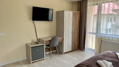 a bedroom with a desk and a tv on a wall at Къща за гости Михаела in Chepelare