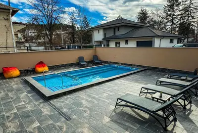 a swimming pool with two lawn chairs and a house at Стоичковата къща гр. Стрелча in Strelcha