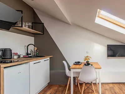 a kitchen with white cabinets and a wooden table at Lion's Bridge Haven - Sofia Central Studio in Sofia