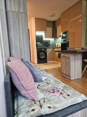 a living room with a couch with pillows and a kitchen at Стаята на Ив in Bansko