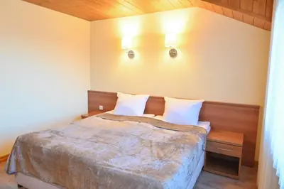 a bedroom with a bed and two lights on the wall at Къща за гости ГРАНИТ in Bansko