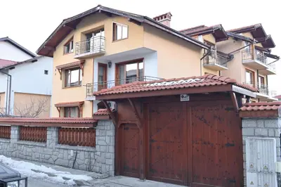 a house with a wooden garage door in front of it at Къща за гости ГРАНИТ in Bansko