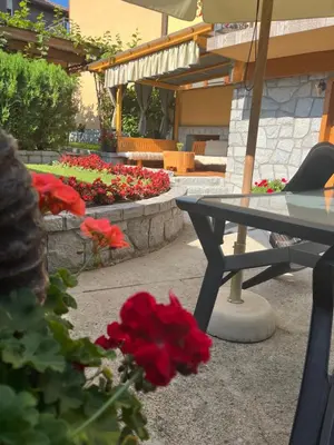 a table and a flower garden with red flowers at Къща за гости ГРАНИТ in Bansko