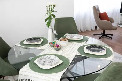 a glass table with green chairs and plates on it at Didi's Central Designer Apartments in Sofia