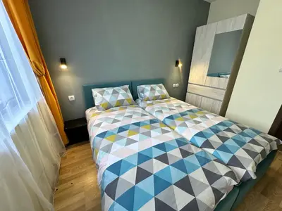 a bedroom with a bed with a checkered blanket at Pine Tree - charming apartment in Bansko