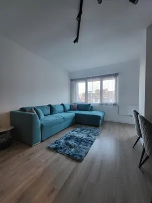 a living room with a blue couch and a wooden floor at KS Rooftop 180° in Bansko