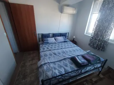 a bedroom with a bed with a blue comforter and a window at Apartment sunny morning in Sandanski