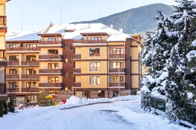 a building in the snow with a road in front at Pirin Sense Apartment Complex in Bansko