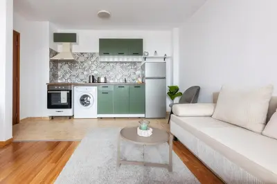 a living room with a couch and a kitchen at Pirin Sense Apartment Complex in Bansko