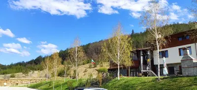a house on a hill with a car parked in front at Alpine Garden Hotel (Trayanovi Dvori) in Simitli