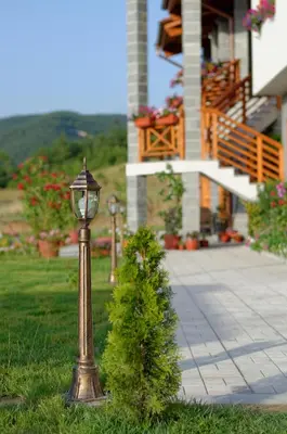 a lamp post in the grass next to a bush at Alpine Garden Hotel (Trayanovi Dvori) in Simitli