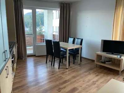a dining room with a table and chairs and a television at Apartment 26А Detelina Residence in Bansko