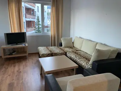a living room with a couch and a tv at Apartment 26А Detelina Residence in Bansko