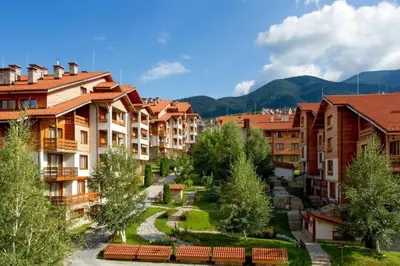 a group of apartment buildings in a city with trees at Family Luxury Private Apartments in 4 star SPA Resort St Ivan Rilski, Bansko in Bansko