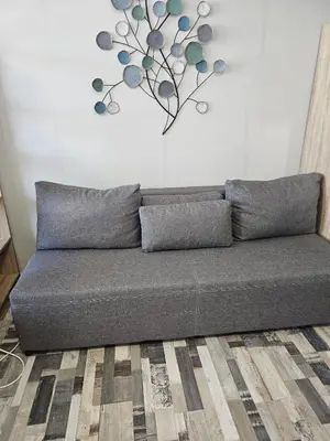 a couch in a living room with a plant on the wall at Studio Apartament 47А- Trakia 54 А in Plovdiv