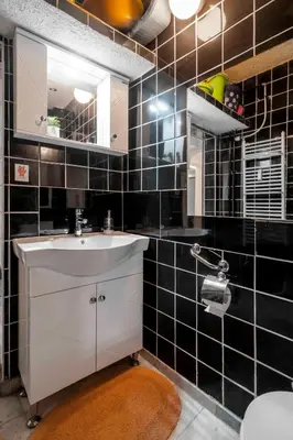 a black tiled bathroom with a sink and a mirror at Cozy Apartment near Vitosha Street by Flat Mаnager in Sofia