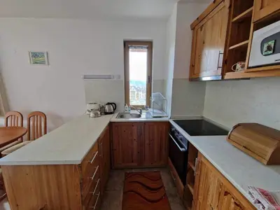 a kitchen with wooden cabinets and a counter top at Saint John Hill Apartment in Bansko