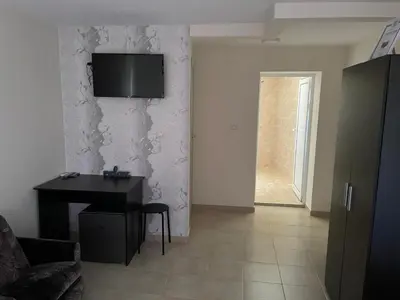 a living room with a table and a television on a wall at ЛАЗАРОВИ in Hisarya