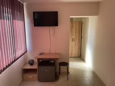 a room with a table and a television on the wall at ЛАЗАРОВИ in Hisarya