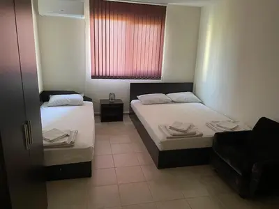 two beds in a small room with a window at ЛАЗАРОВИ in Hisarya