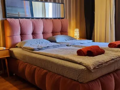 a large bed with a pink headboard with two stuffed animals on it at Central Apartment in Sofia