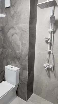 a bathroom with a white toilet and a stone wall at Димоти Апартхотел in Sofia